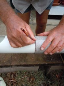 Marking a straight line around the pipe by using a piece of lino to ensure the line is straight