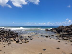 A beach in queensland with the ocean in the background a rocks on both sides